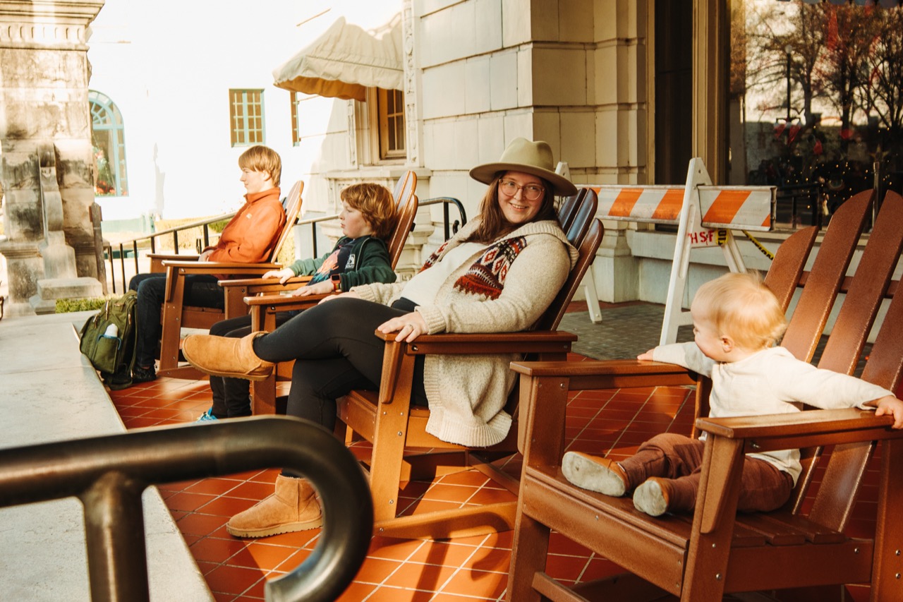 Four people sitting in rocking chairs on a porch